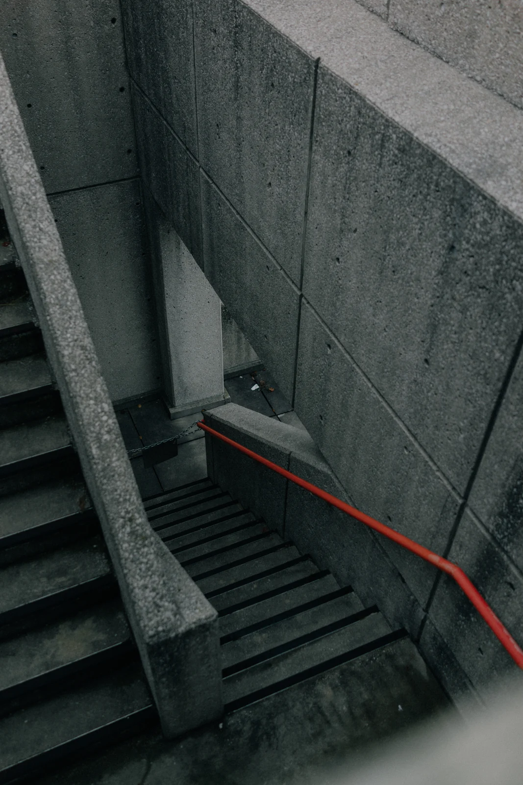 Concrete stairs and a red handrail in a brutalist stairwell, graded with GX-05 Labyrinth