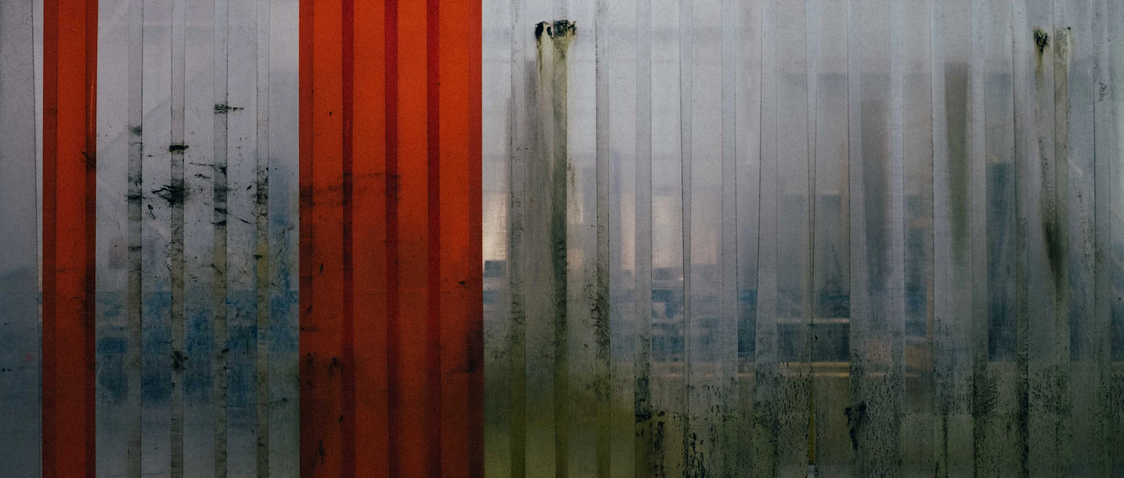 Red and white ribbed plastic curtains in an industrial doorway, graded with GX-04 Clean Room