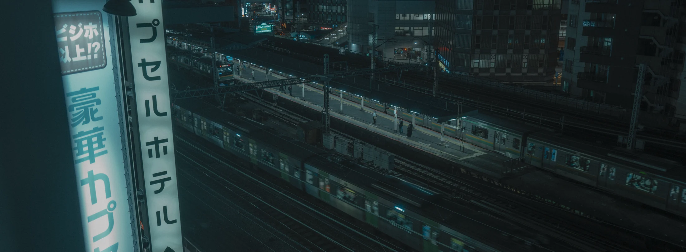 A capsule-hotel sign above night railway tracks, graded with GX-06 Capsule