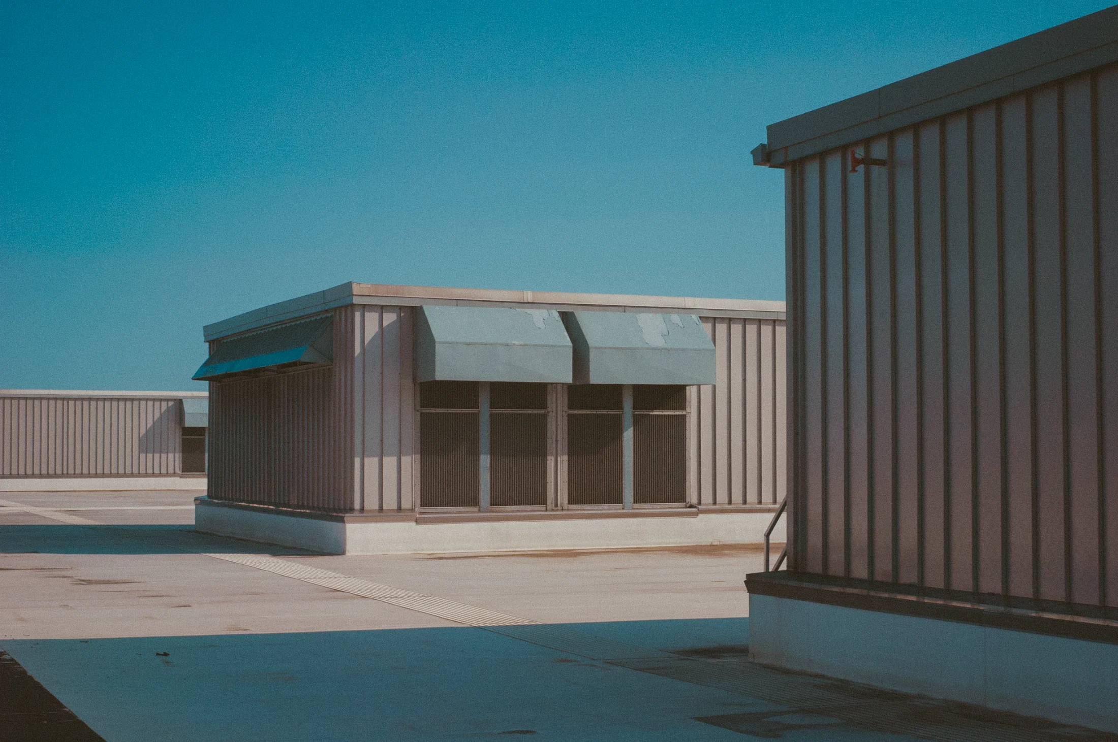 A pink and cream warehouse under a clear teal sky, graded with GX-06 Teal Hour