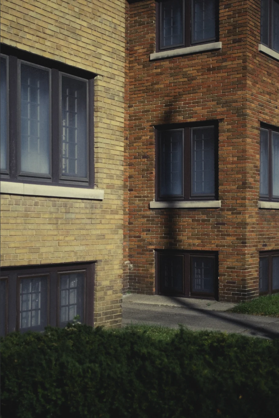 A brick and stone apartment corner in low sun, graded with GX-03 Bloc 02