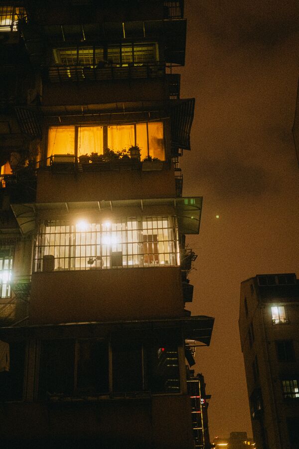 Night apartment balconies lit orange and white against a sodium-hazed sky